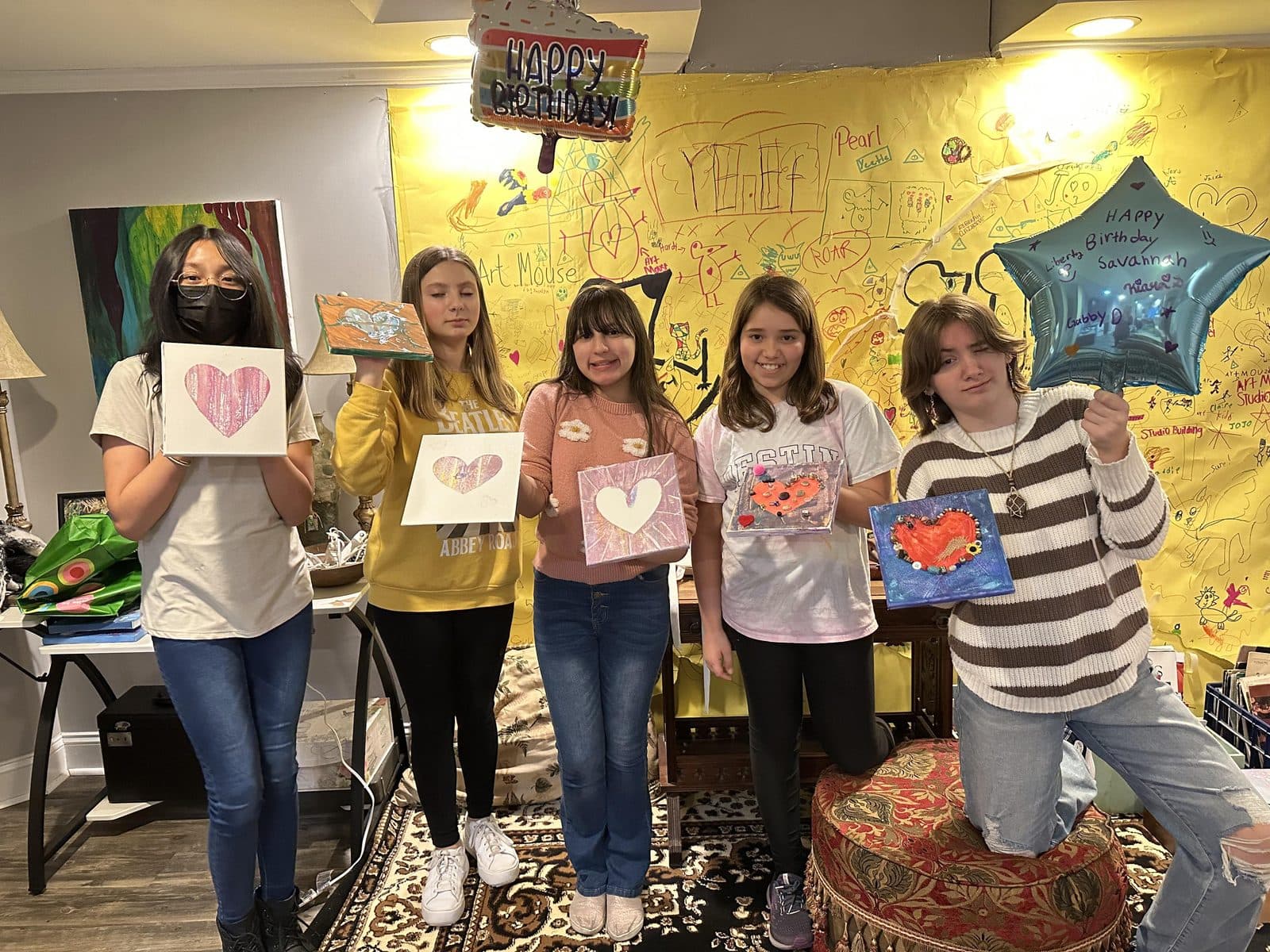 A birthday group showing off their matching heart paintings